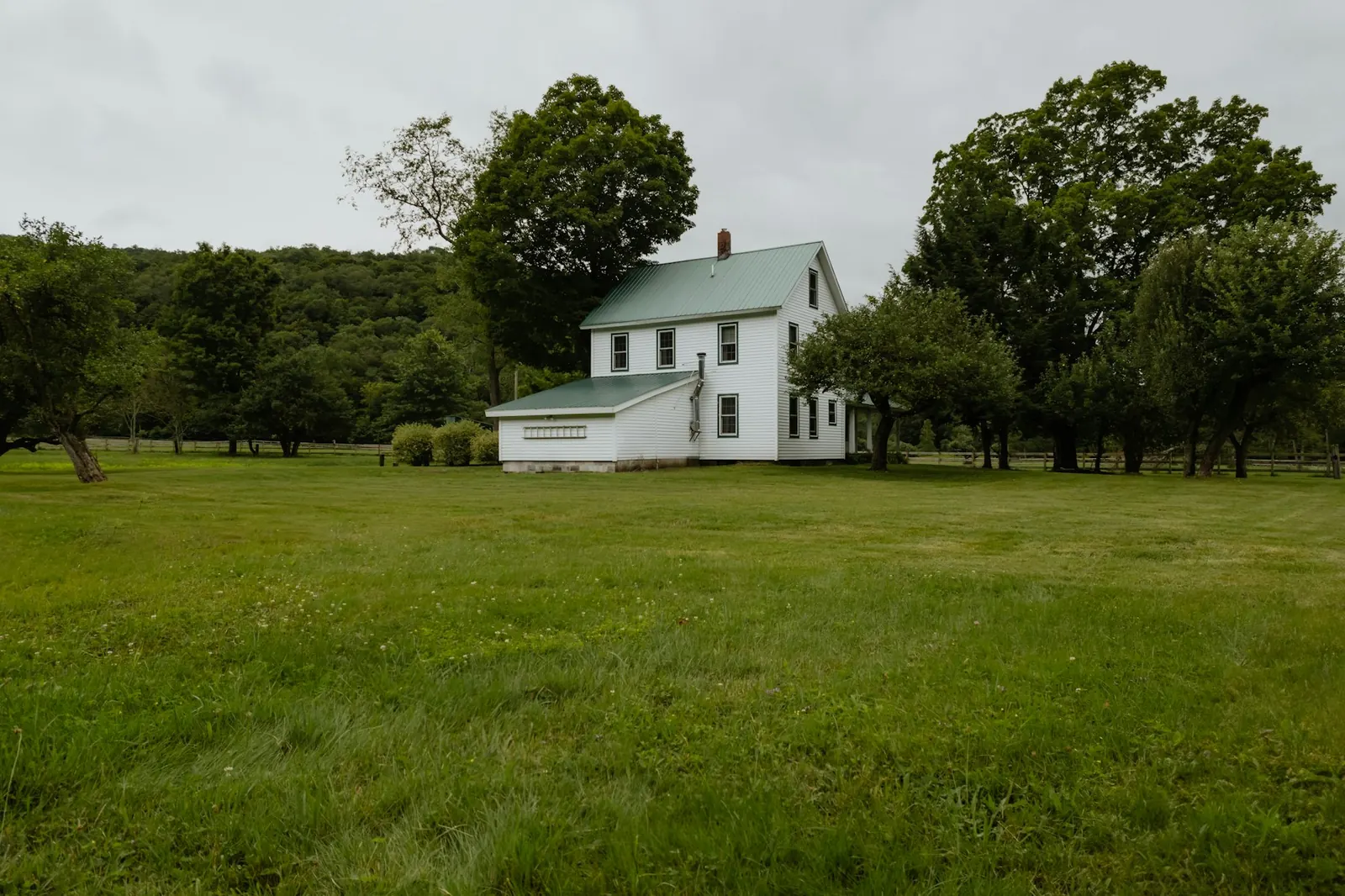 White country house surrounded by a green field in upstate New York.